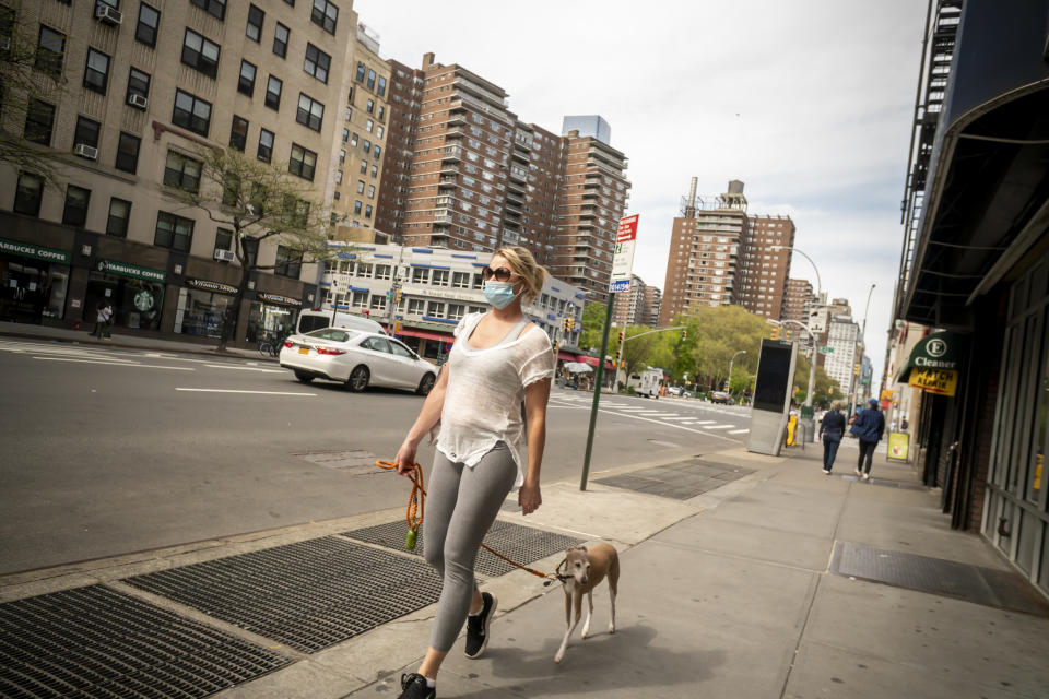 Woman wearing a mask walks with her dog in New York on Saturday. Source: AAP