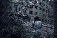 A Ukrainian woman walks amid the debris of a residential building following night shelling in Mykolaiv, Ukraine, Tuesday, Aug. 2, 2022. (AP Photo/Kostiantyn Liberov)