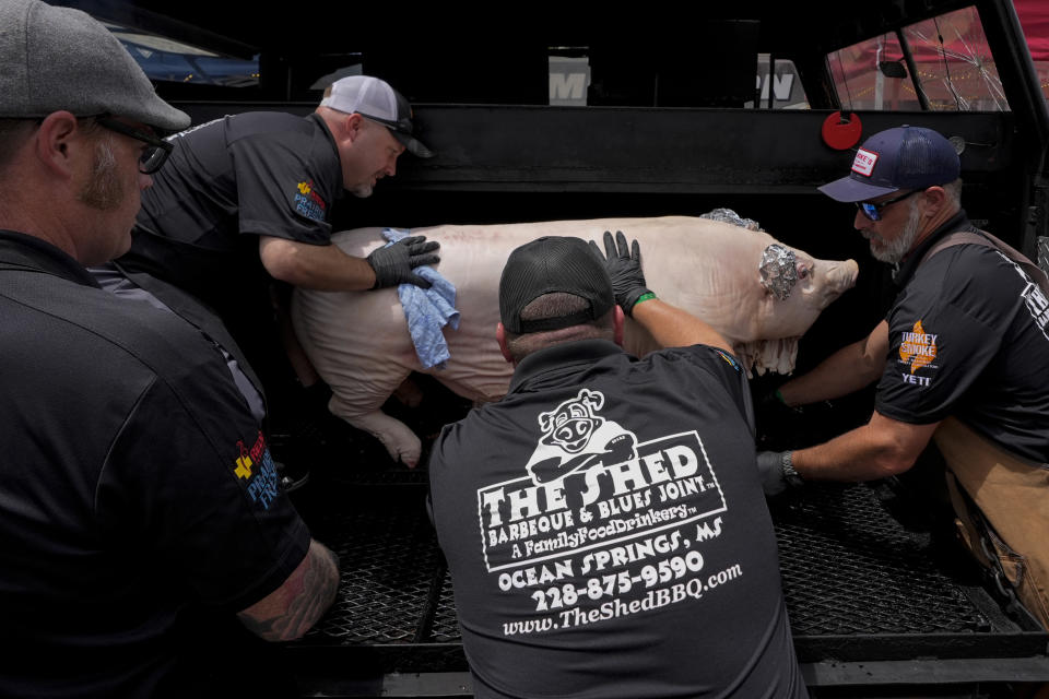 Shaun Stecklein, left, Jeff Fritz, Nick Ray and Buddy Aucoin, right, of The Shed BBQ and Blues Joint team load a whole hog into a cooker as they compete at the World Championship Barbecue Cooking Contest, Friday, May 17, 2024, in Memphis, Tenn. (AP Photo/George Walker IV)