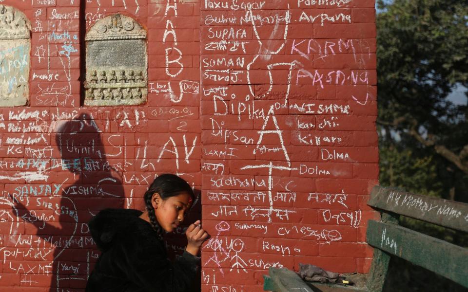 A Nepalese devotee writes her name on a Saraswati templ - AP