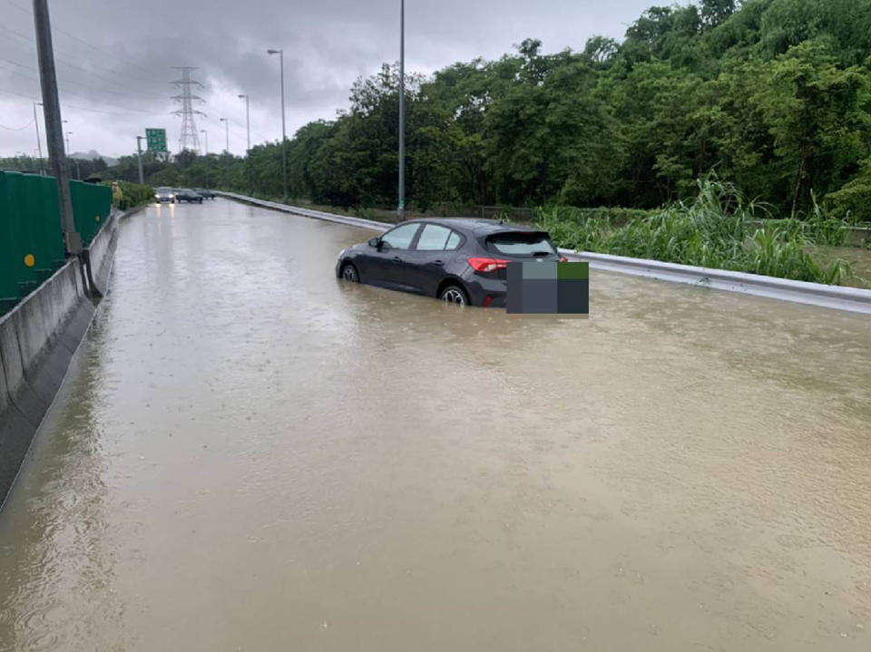 豪雨狂炸，高雄市燕巢區通往國10方向的道路20日上午積水逾半個輪胎深，有民眾車輛拋錨深陷其中，經向消防隊通報救援才得以脫困。（高市消防局提供）