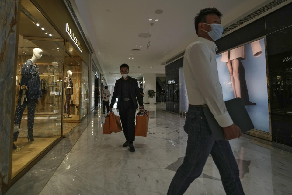 Residents wearing face masks walk through the reopened retail shops inside a mall after it was closed due to COVID-19 restrictions in Beijing, Sunday, May 29, 2022. (AP Photo/Andy Wong)