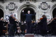 Michel Dietlin prepares to conduct striking musicians of the orchestra outside the Palais Garnier opera house Saturday, Jan. 18, 2020 in Paris. As some strikers return to work, with notable improvements for train services that have been severely disrupted for weeks, more radical protesters are trying to keep the movement going. (AP Photo/Kamil Zihnioglu)