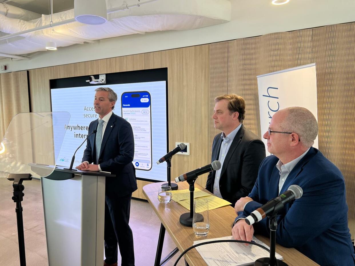 Premier Tim Houston, left, speaks at the announcement of the pilot project. Dr. Aaron Smith, medical executive director of Nova Scotia Health's northern zone, centre, and Scott McKenna, chief information information officer at Nova Scotia Health and IWK Health, look on. (Jean Laroche/CBC - image credit)