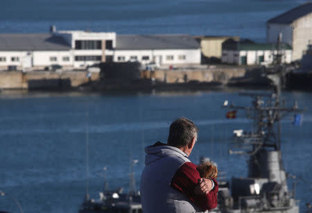 A man holds a dog as he looks at ships at the naval base where the missing at sea ARA San Juan submarine sailed from, in Mar del Plata, Argentina November 18, 2017. REUTERS/Marcos Brindicci