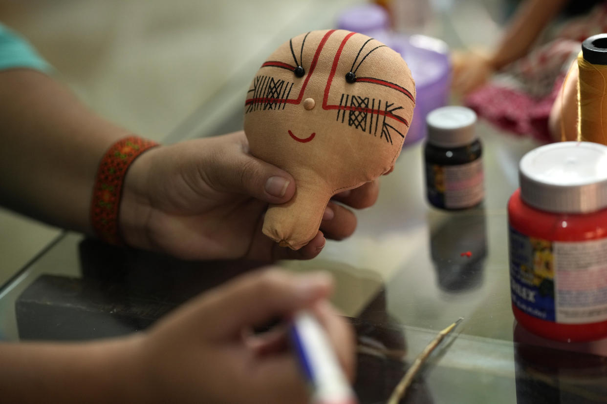 Atyna Pora, of Brazil's Anambe indigenous group, paints an indigenous doll, at the sewing workshop in her home in Rio de Janeiro, Brazil, Tuesday, May 24, 2022. Pora and her mother Luakam Anambe who make the dolls bearing faces and body paints of different Indigenous groups, have sold more than 5,000 of their dolls. (AP Photo/Silvia Izquierdo)