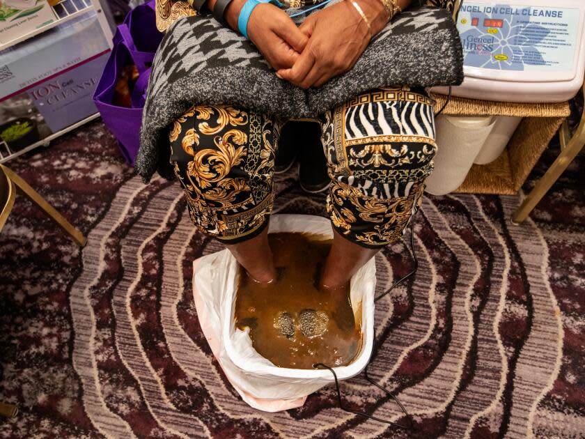 A woman soaks her feet in murky brown liquid.