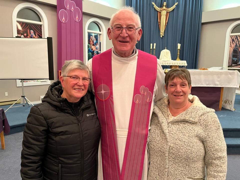 Monsignor Joe Barton (centre) was a special guest at St. Patrick's in the Town of Burin Sunday as some 50 Catholics gathered for the final mass at the church, marking an end to more than two centuries of formal church presence in the community. Sharing a moment with Monsignor Barton were Rita Lundrigan (left) and Bella Keating. (Terry Roberts/CBC - image credit)