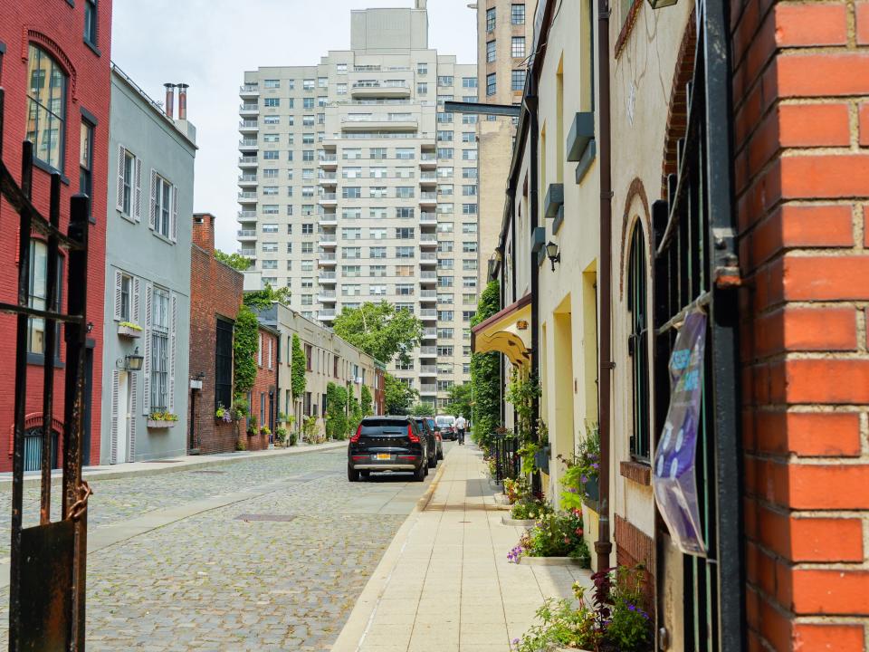 A red brick gated cobblestone street lined with mews.