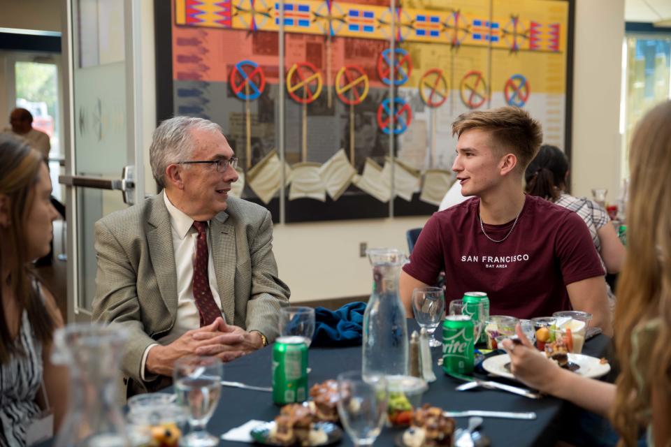 South Dakota State University President Barry Dunn (left) visits with Marcus Harming (right) and other SDSU students at the President's Dinner in the new American Indian Student Center on campus.