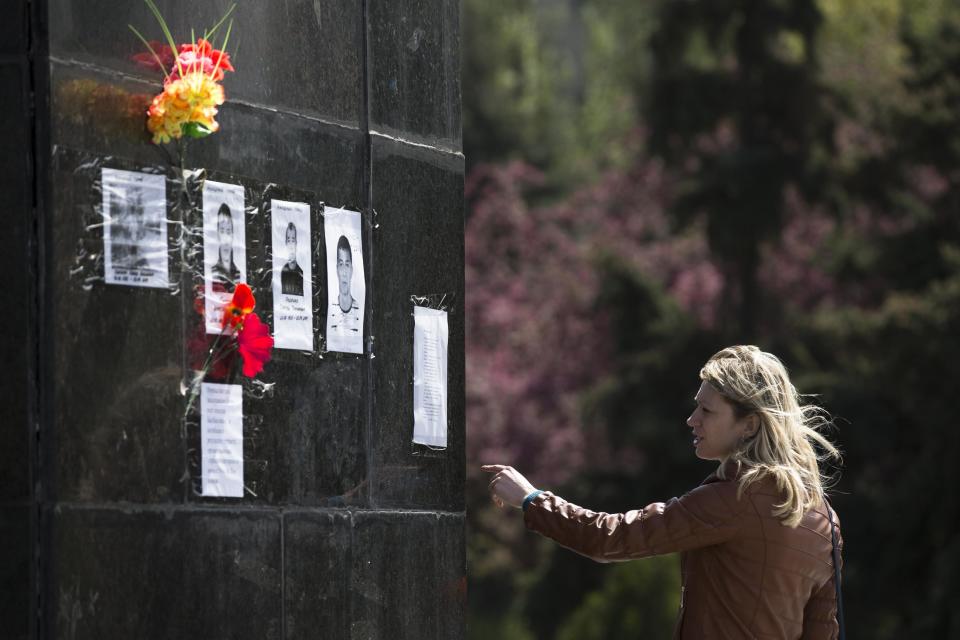 A woman looks at portraits of pro-Russia militia members killed during clashes with the Ukrainian Army attached to the pedestal of the monument of former Soviet leader Vladimir Lenin in Slovyansk, Ukraine, Monday, April 28, 2014. Armed pro-Russian insurgents are seeking increased autonomy in the eastern region of Ukraine, from the interim government in Kiev. (AP Photo/Alexander Zemlianichenko)