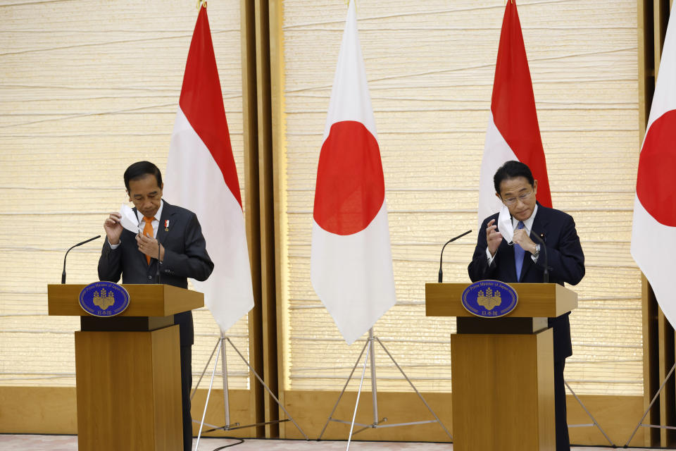 Indonesian President Joko Widodo, left, and Japan's Prime Minister Fumio Kishida take off a facial mask as they start a joint news conference at the prime minister's official residence in Tokyo Wednesday, July 27, 2022. (Kiyoshi Ota/Pool Photo via AP)