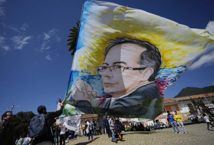 A supporter of Historical Pact coalition presidential candidate Gustavo Petro, holds a flag with the image of Petro before a closing campaign rally in Zipaquira, Colombia, Sunday, May 22, 2022. Elections are set for May 29. (AP Photo/Fernando Vergara)