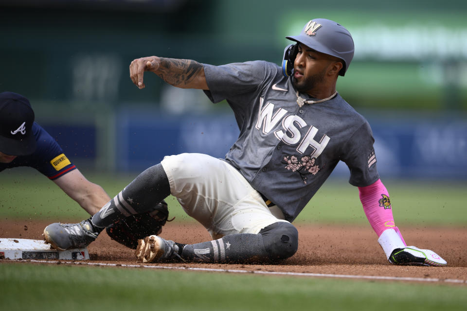 Washington Nationals' Eddie Rosario, right, slides safely into third against Atlanta Braves third baseman Austin Riley, left, on a sly out by Luis Garcia Jr. during the first inning of a baseball game, Saturday, June 8, 2024, in Washington. (AP Photo/Nick Wass)