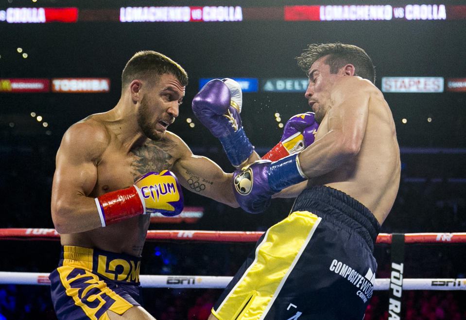 FILE - In this April 12, 2019, file photo, Vasiliy Lomachenko, left, from Ukraine, hits Anthony Crolla, from Britain, during a WBA and WBO lightweight title boxing match in Los Angeles. In ordinary times Vasiliy Lomachenko and Teofimo Lopez would be the fight of the fall, a lightweight title match about as compelling as it gets in the boxing world these days. Instead of a big crowd, the only fans at the MGM Grand conference center will be a few hundred sponsors and first responders with special invites. And, instead of pay-per-view, the fight will be televised live on ESPN, guaranteeing a larger audience than a pay-per-view even if the money isn’t nearly the same. (AP Photo/Damian Dovarganes, File)