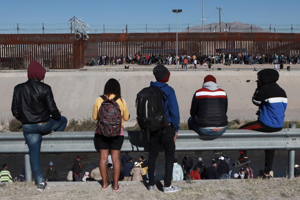 Migrants watch others stand next to the border wall in Ciudad Juarez, Mexico, Dec. 21, 2022, on the other side of the border from El Paso, Texas.