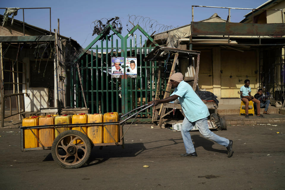 A Nigerian man pushs his wheelbarrow by the closed central market in Kaduna, Nigeria, Saturday, Feb. 16, 2019. Nigeria's electoral commission delayed the presidential election until Feb. 23, making the announcement a mere five hours before polls were set to open Saturday. (AP Photo/Jerome Delay)