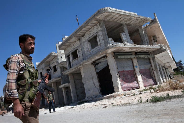 A Rebel walks in front of a destroyed building in the village of Al-Rami, in the northwestern Syrian province of Idlib, on June 22, 2013