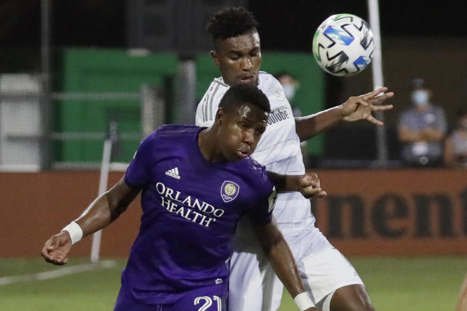 Orlando City midfielder Andres Perea (21) hits the ball as Los Angeles FC midfielder Jose Cifuentes (11) closes in during the second half of an MLS soccer match, Friday, July 31, 2020, in Orlando, Fla. (AP Photo/John Raoux)