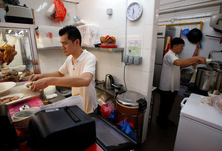 Hawker Derrick Lee, 30, and his mentor Zhu Yong Kun, 65, prepare chicken rice at their stall in a hawker centre in Singapore June 30, 2016. REUTERS/Edgar Su