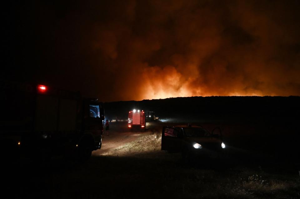 Firefighting vehicles are seen as smoke billows from a wildfire near the city of Volos, central Greece, on July 26 (AFP via Getty Images)