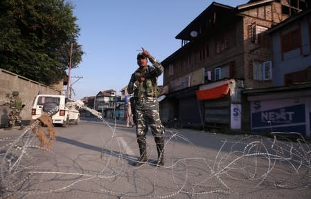 An Indian security personnel stands guard on a deserted road during restrictions after scrapping of the special constitutional status for Kashmir by the Indian government, in Srinagar