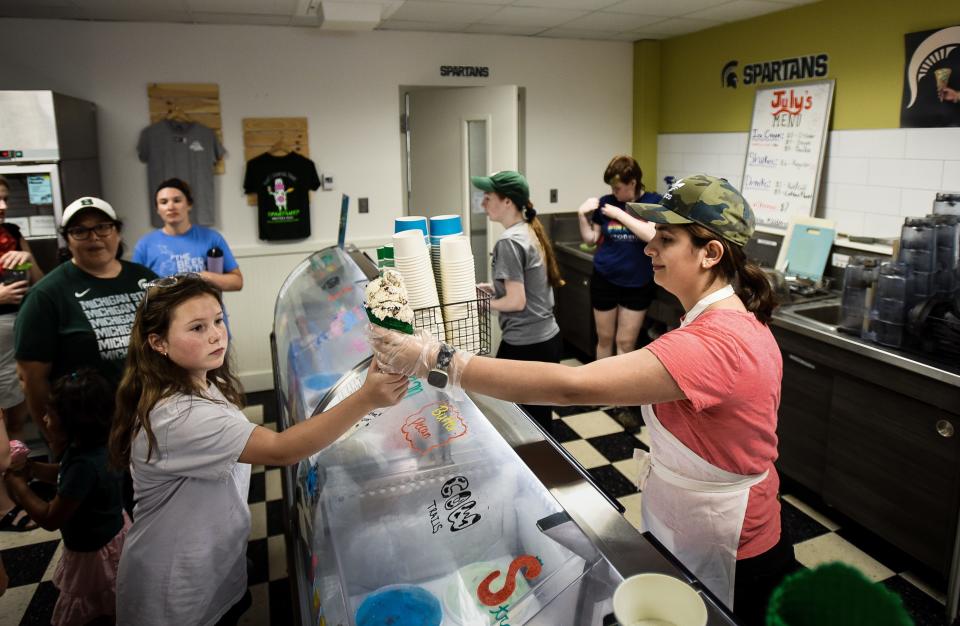 MSU Dairy Store employee Noel Tom serves a young customer Friday, July 8, 2022, at the renowned dairy store on the campus of Michigan State University. Tom graduated in May after studying dietetics, and plans to pursue a master's degree.