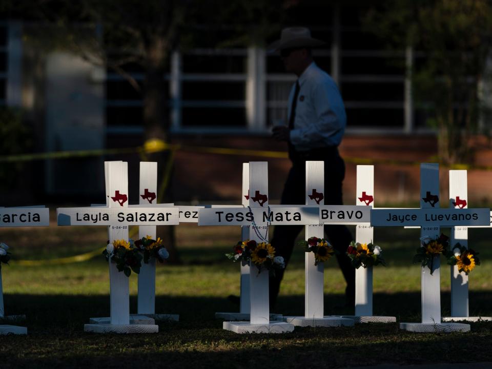 A law enforcement personnel walks past crosses bearing the names of Tuesday's shooting victims at Robb Elementary School in Uvalde, Texas, Thursday, May 26, 2022.