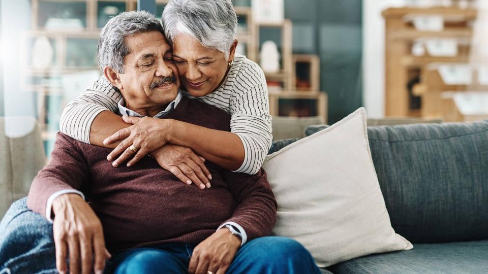 Cropped shot of a cheerful elderly woman hugging her husband who's in a wheelchair at home during the day.