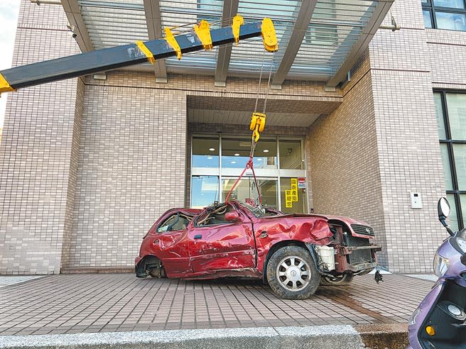 台東吳姓拖吊車司機不滿理賠遭刁難，竟將廢棄車吊掛堵在保險公司門口。（蔡旻妤攝）