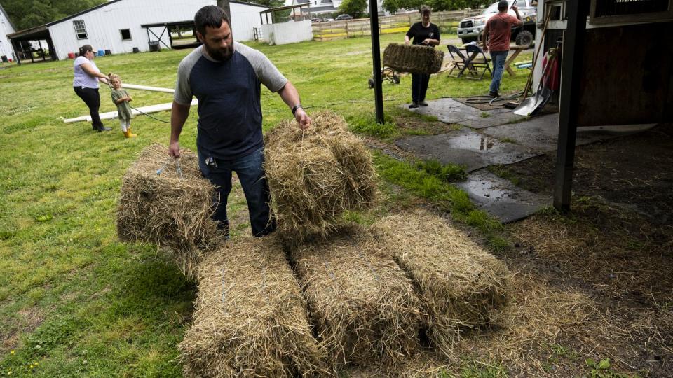 Jarred Bragg helps move bales of hay during a clean up event for Trails of Purpose, May 20, 2023, in Chesapeake, Va., ahead of the opening of their new location in Virginia Beach, Va. (Billy Schuerman/The Virginian-Pilot via AP)