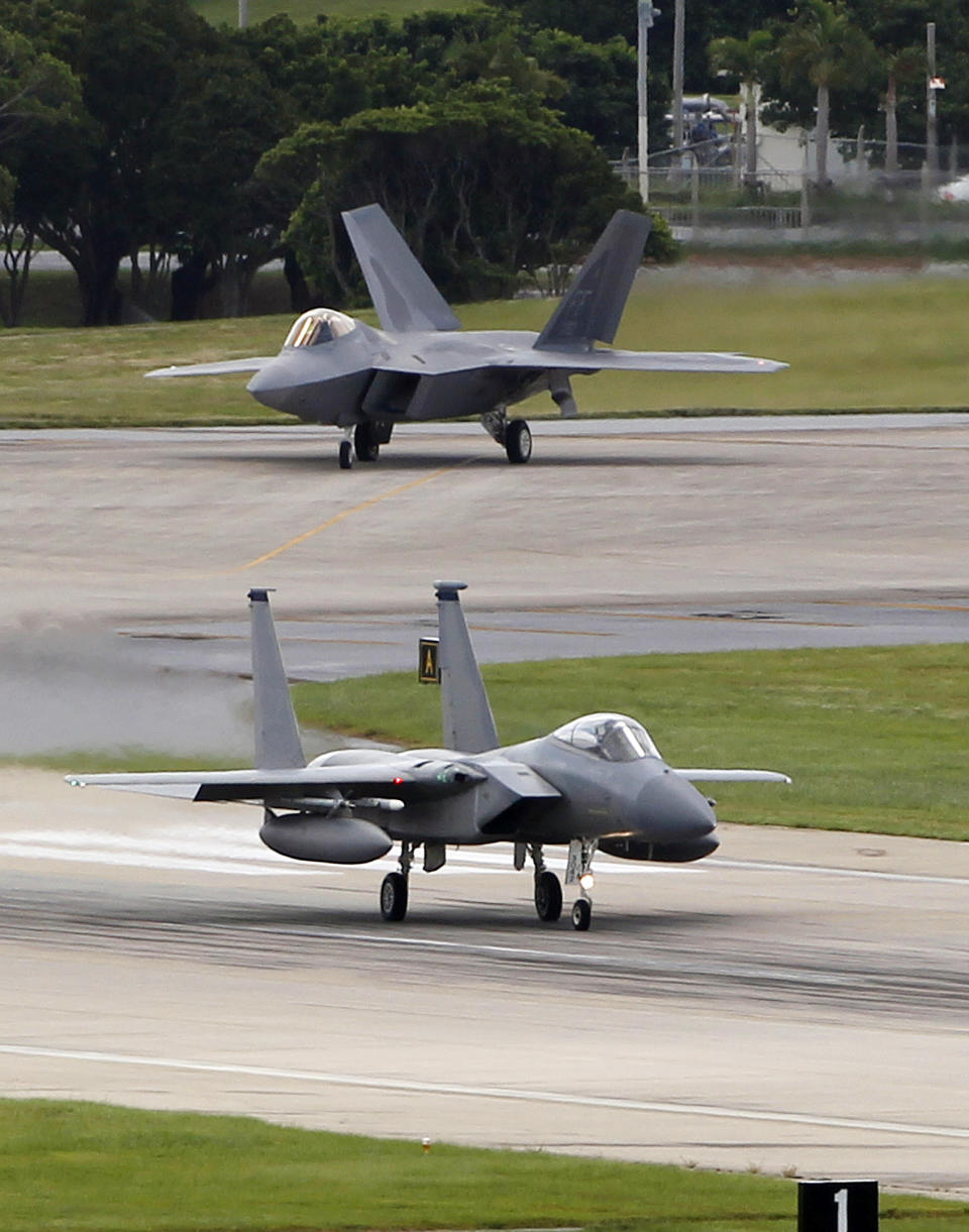In this Aug. 14, 2012 photo, a U.S. Air Force F-22 Raptor, top, waits as an F-15 Eagle begins its take off run at Kadena Air Base on the southern island of Okinawa, in Japan. The deployment of a dozen F-22 stealth fighters to Japan has so far gone off without a hitch as the aircraft are being brought back into the skies in their first overseas mission since restrictions were imposed over incidents involving pilots getting dizzy and disoriented, a senior U.S. Air Force commander told the Associated Press on Thursday Aug. 30, 2012. (AP Photo/Greg Baker)