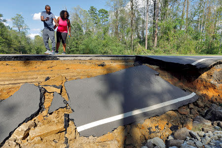 Passersby look at a section of washed-out road damaged by flood waters in the aftermath of Hurricane Florence, now downgraded to a tropical depression, in Currie, North Carolina, U.S., September 18, 2018. REUTERS/Jonathan Drake
