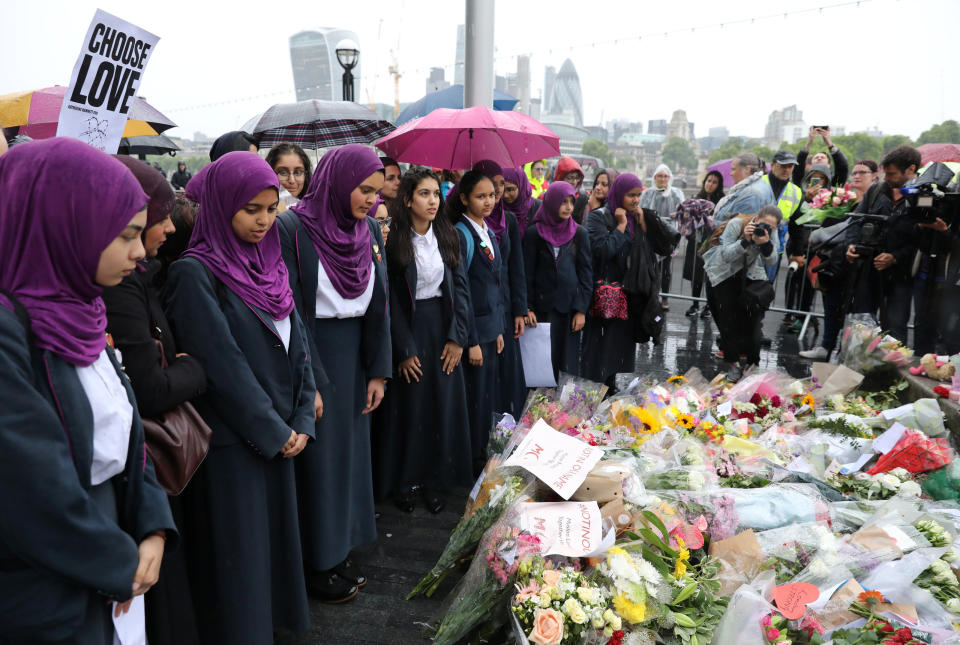 School girls look at floral tributes after a vigil to remember the victims of the attack.&nbsp;