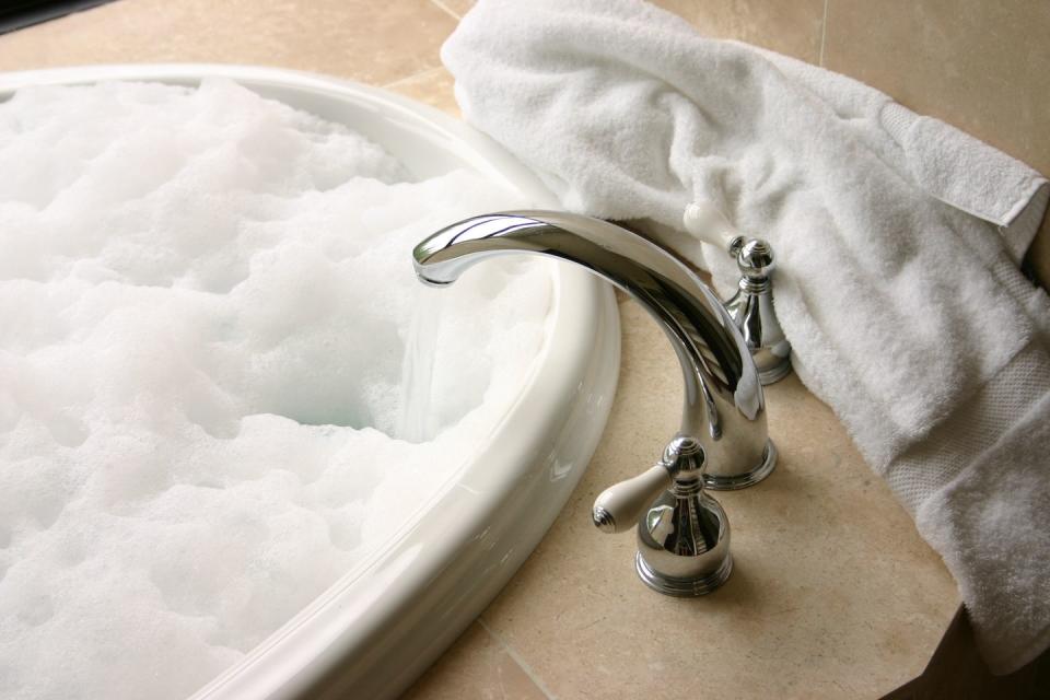 bubble bath with chrome faucet, travertine, towel