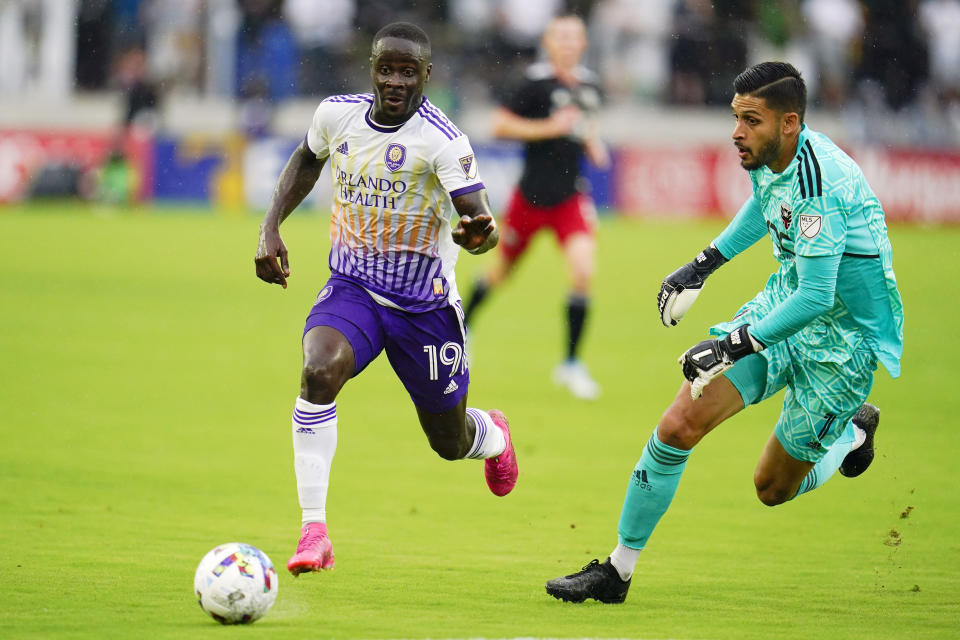 FILE - Orlando City forward Benji Michel, left, attacks as D.C. United goalkeeper Rafael Romo leaves his penalty area to defend during the first half of an MLS soccer match, Sunday, July 31, 2022, in Washington. Orlando City’s pursuit of its first trophy in the U.S. Open Cup is personal for Benji Michel, who grew up in Orlando and was signed by the Lions as a homegrown player. (AP Photo/Julio Cortez, File)