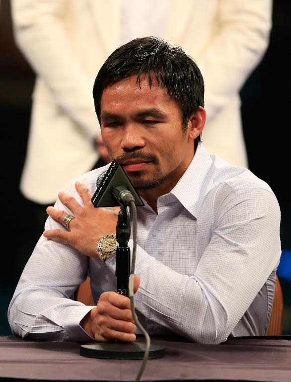 Manny Pacquiao points to his right shoulder during the post-fight news conference after losing to Floyd Mayweather in their welterweight unification championship bout on May 2, 2015