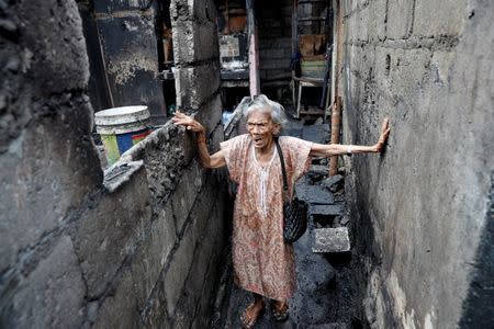 A woman walks in an alley next to her house destroyed by a fire at a residential district in Quezon City, Metro Manila, Philippines, March 8, 2018. REUTERS/Erik De Castro