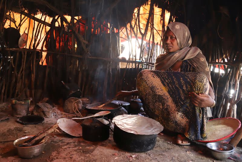 Internally displaced Ethiopian cooks sorghum to feed her children inside her hut in Tuli Guled