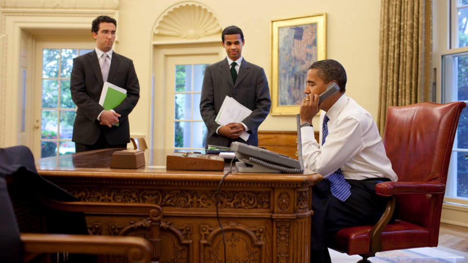 President Obama talks on the phone in the Oval Office as Wear and White House staffer Paul Monteiro look on. 