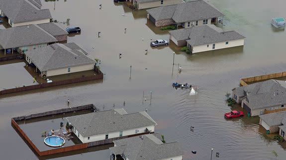 In this aerial photo a boat motors between flooded homes after heavy rains inundating the region Saturday, Aug. 13, 2016, in Hammond, La.