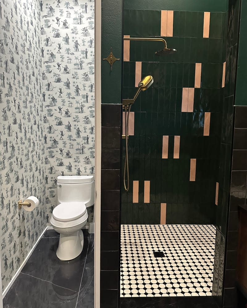 Wallpapered toilet area and pink and green tiles in shower of newly renovated bathroom