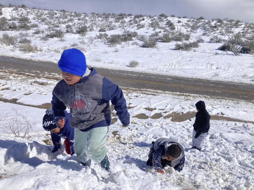 Children play in the snow near the Cajon Pass in Oak Hills, Calif., on Wednesday, March 1, 2023, as a fresh round of snowfall blanketed the San Bernardino Mountains east of Los Angeles. Up to 5 feet of snow fell in some areas, stranding some residents. (AP Photo/Eugene Garcia)
