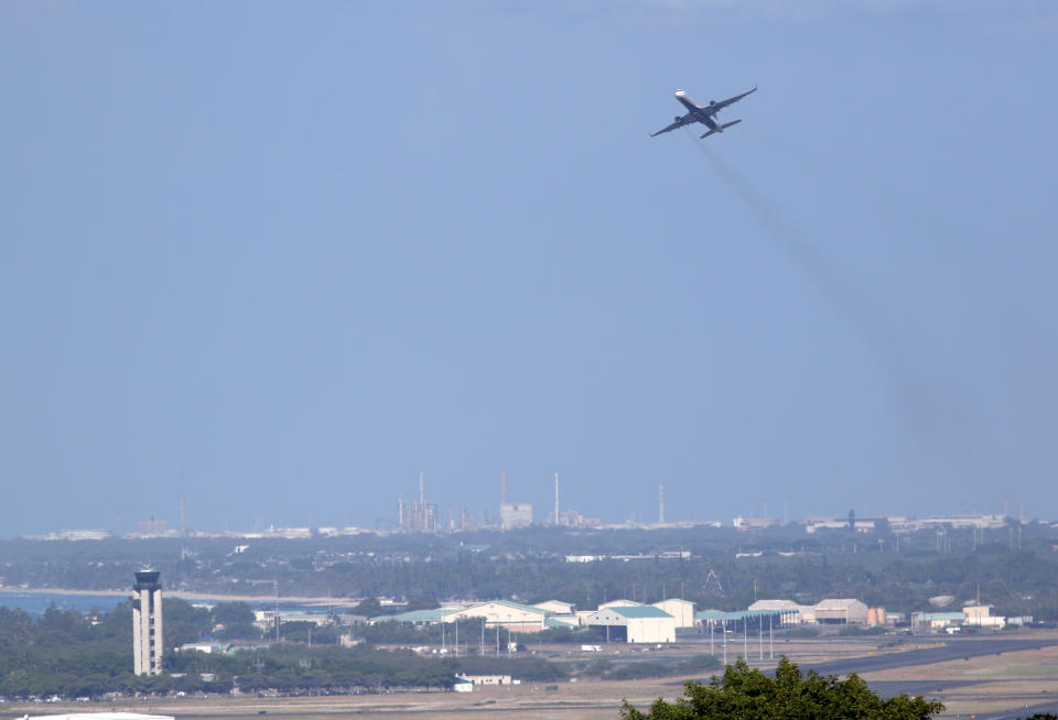 Oahu's power plants are shown on the horizon as an airliner takes off from the international airport in Honolulu, Wednesday, Aug. 24, 2022. As Hawaii transitions toward its goal of achieving 100% renewable energy by 2045, the state's last coal-fired power plant closed this week ahead of a state law that bans the use of coal as a source of electricity beginning in 2023. (AP Photo/Caleb Jones)