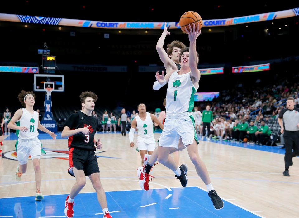 Andrew Smith of Bishop McGuinness goes to the basket past Bishop Kelley's Brady Shultz.