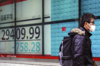 A man wearing a protective mask walks in front of an electronic stock board showing Japan's Nikkei 225 index at a securities firm Friday, Feb. 26, 2021, in Tokyo. Asian shares skidded Friday after rising bond yields triggered a broad sell-off on Wall Street that erased the markets gain for the week and handed the Nasdaq composite index its steepest loss since October. (AP Photo/Eugene Hoshiko)