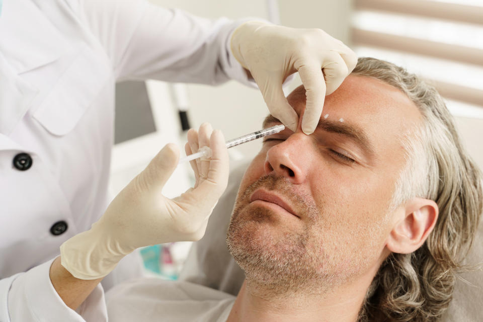 Female doctor making marks on client's face before filler injections in aesthetics medical clinic