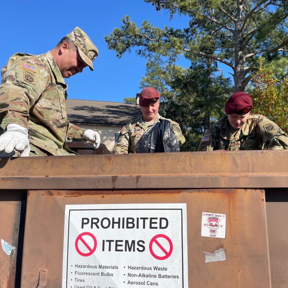 Command Sgt. Maj. Gregory Seymour, far left, pitches in to help remove trash from dumpsters in late February, after trash started to pile around the dumpsters earlier this year.