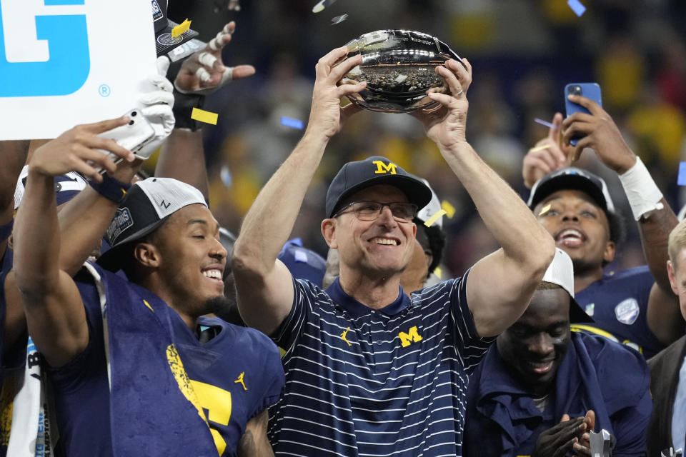 Michigan head coach Jim Harbaugh holds the trophy as he celebrates with his team after defeating Purdue in the Big Ten championship NCAA college football game, early Sunday, Dec. 4, 2022, in Indianapolis. Michigan won, 43-22. (AP Photo/AJ Mast)
