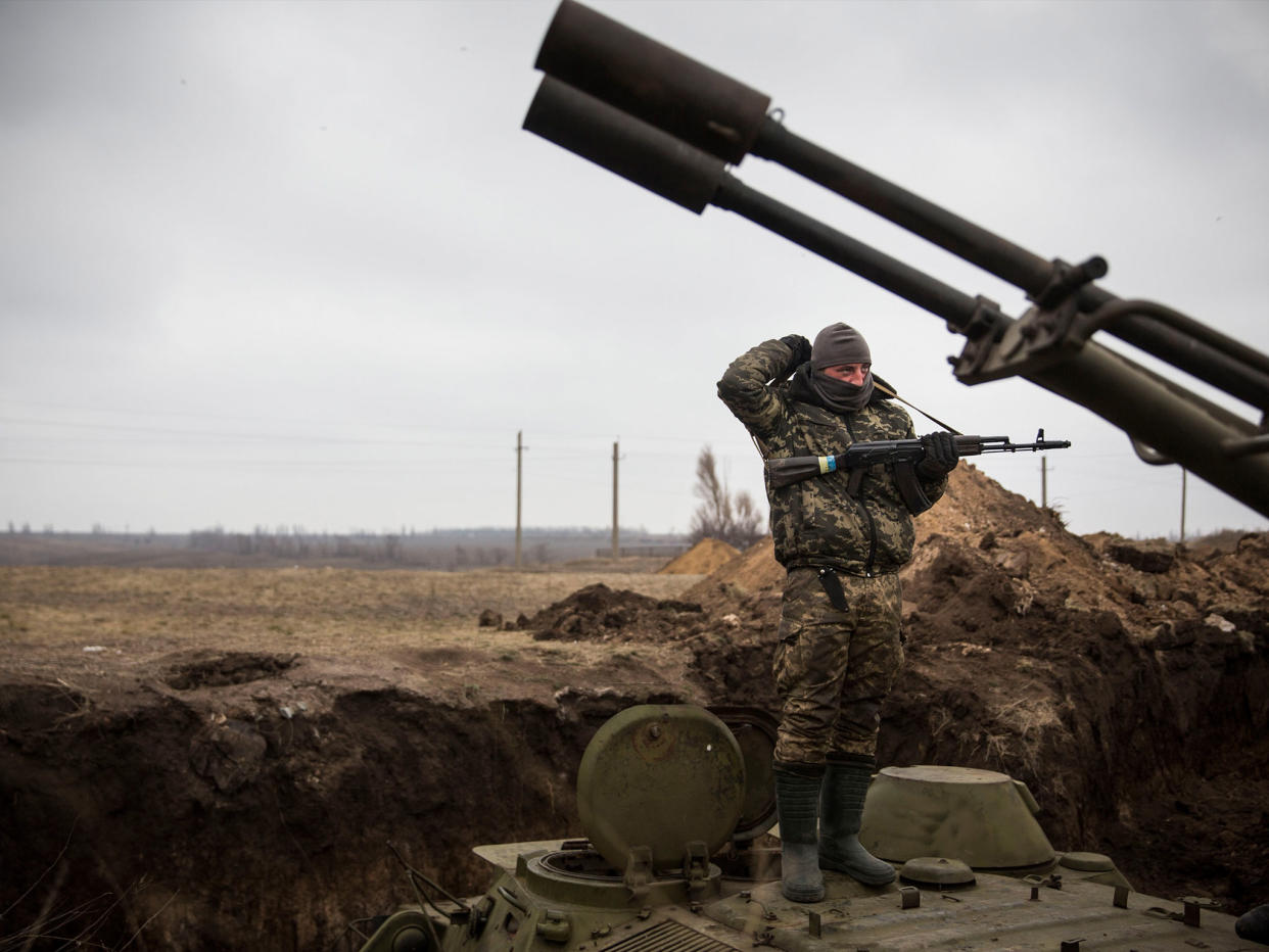 A Ukrainian soldier stands on top of an armored personal carrier in a trench: Getty